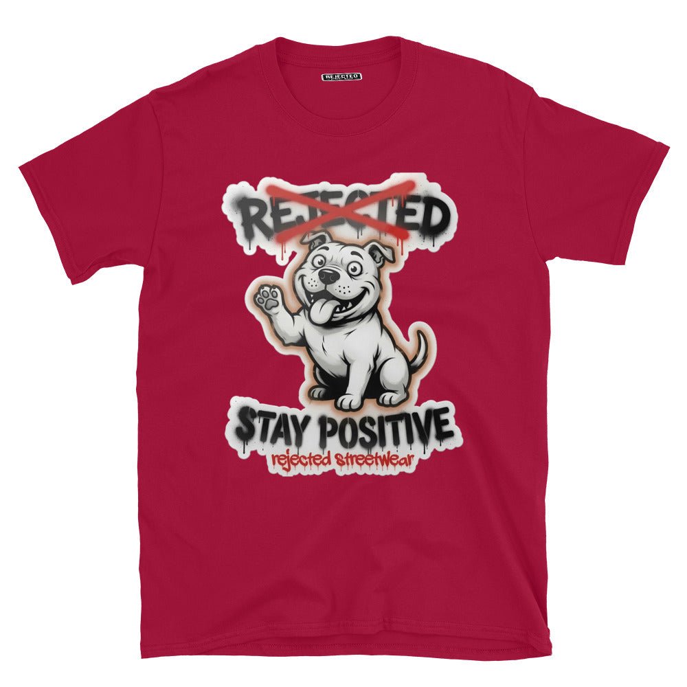 Stay Positive pit bull tee — white bully pup sitting with one paw raised, REJECTED crossed out in red